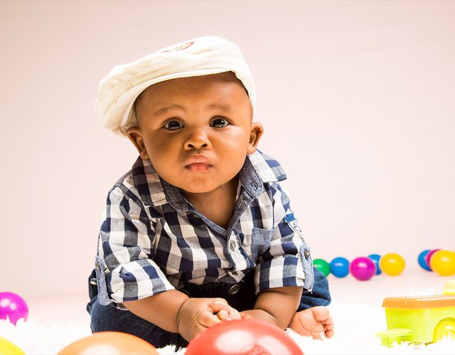 A baby in a cap and checked shirt in the studio