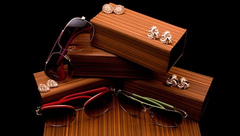 Sunglasses and cufflinks styled on wooden boxes