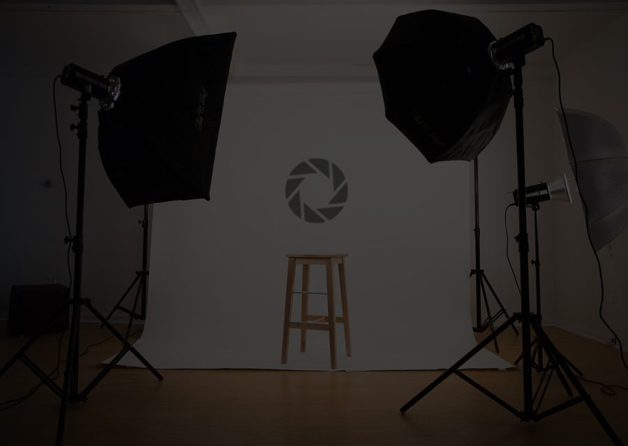The Optix studio: two softboxes and a stool in front of a white wall with the aperture logo