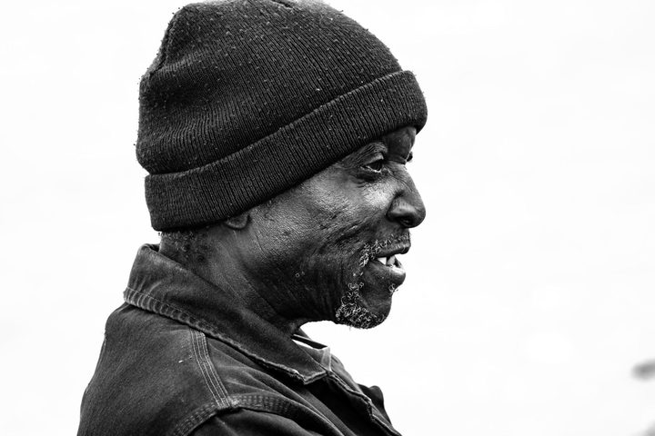 Black and white portrait of an older man in a beanie, in profile