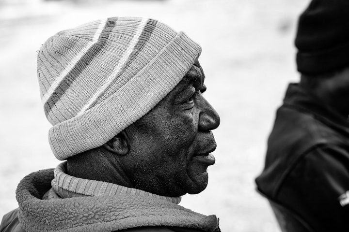 Black and white portrait of a man in a striped beanie, in profile